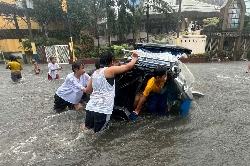 Residents push a tricycle along a flooded street due to heavy monsoon rains at Mandaluyong, Metro Manila, Philippines, Monday, Aug. 17, 2026. (AP Photo/Joeal Calupitan)