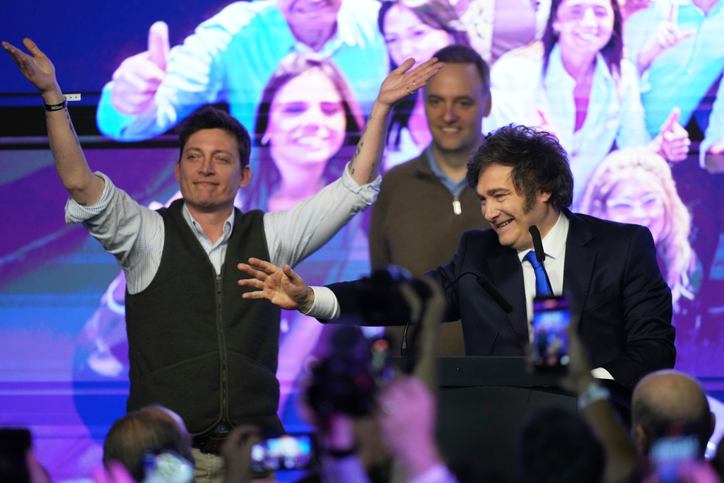 Argentina's President Javier Milei, right, and his advisor Santiago Caputo, wave to supporters after winning in legislative midterm elections in Buenos Aires, Argentina, Sunday, Oct. 26, 2025. (AP Photo/Rodrigo Abd)