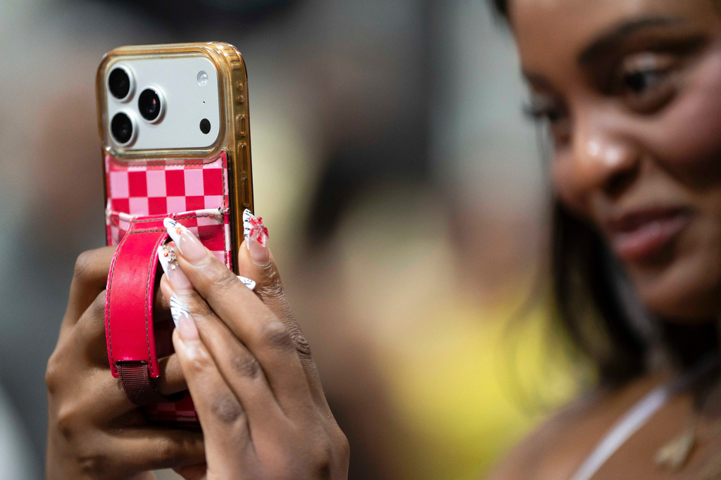 Phoenix-based content creator Aiesha Beasley films during the grand opening of Padeland, a venue for the racket sport padel in Chandler, Ariz., Thursday, Aug. 13, 2026. (AP Photo/Rebecca Noble)