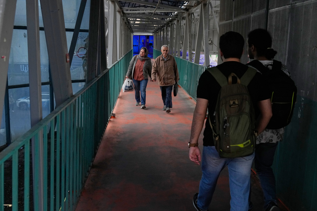 People walk across an overpass in downtown Tehran, Iran, Tuesday, Feb. 24, 2026. (AP Photo/Vahid Salemi)