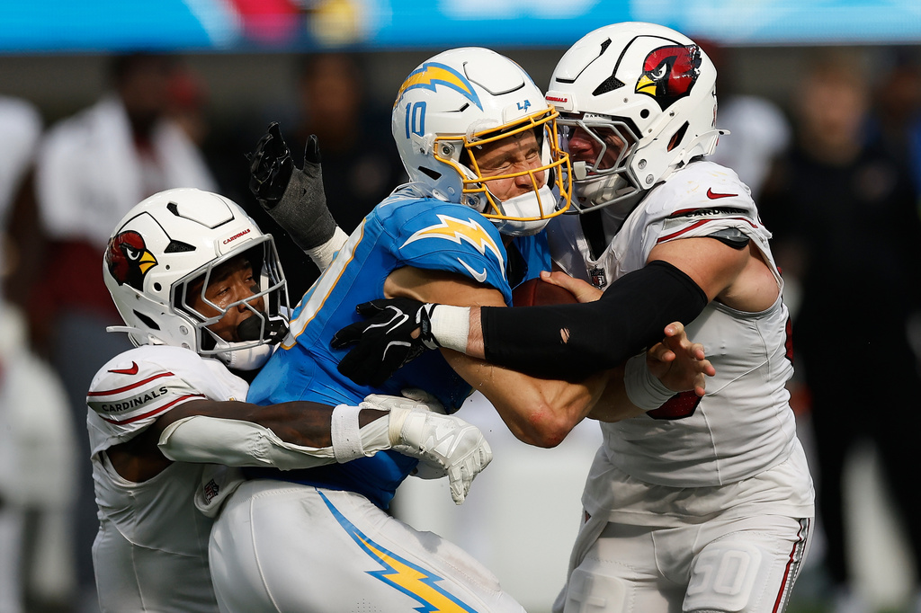 Los Angeles Chargers quarterback Justin Herbert, middle, is sacked by Arizona Cardinals safety Budda Baker, left, and linebacker Jack Gibbens during the second half of an NFL football game, Sunday, Sept. 13, 2026, in Inglewood, Calif. (AP Photo/Caroline Brehman)
