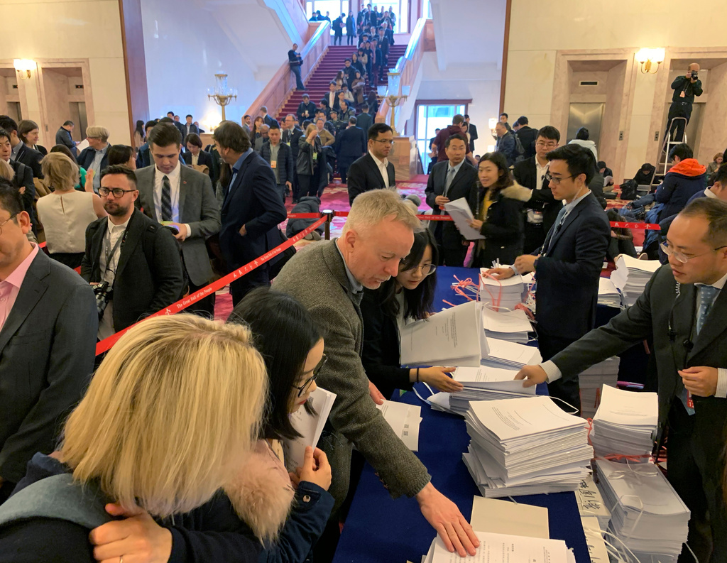 Christopher Bodeen, center, picks up documents on the day of the opening ceremony for the National People's Congress at the Great Hall of the People in Beijing, on March 5, 2019. (AP Photo/Ng Han Guan)