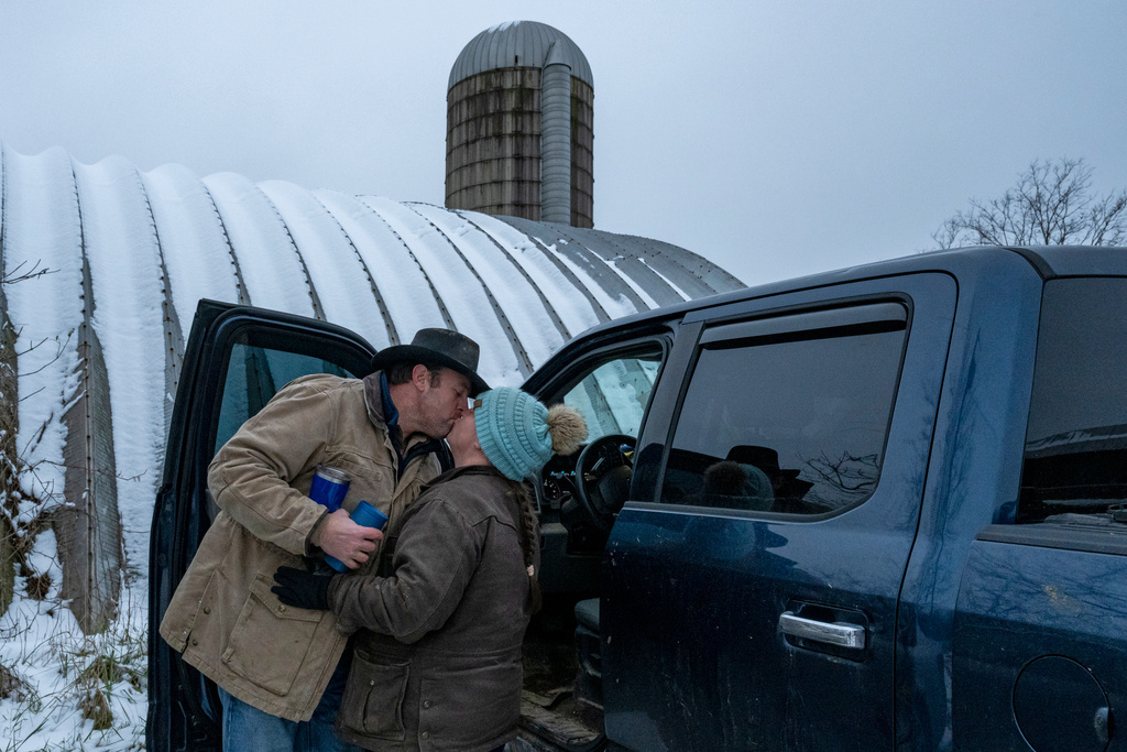 Josh, left, and Ashley Pyles kiss each other before Josh heads to another farm to check on a herd of cattle in Henry County, Ky., Saturday, Dec. 13, 2025. (AP Photo/Michael Swensen)