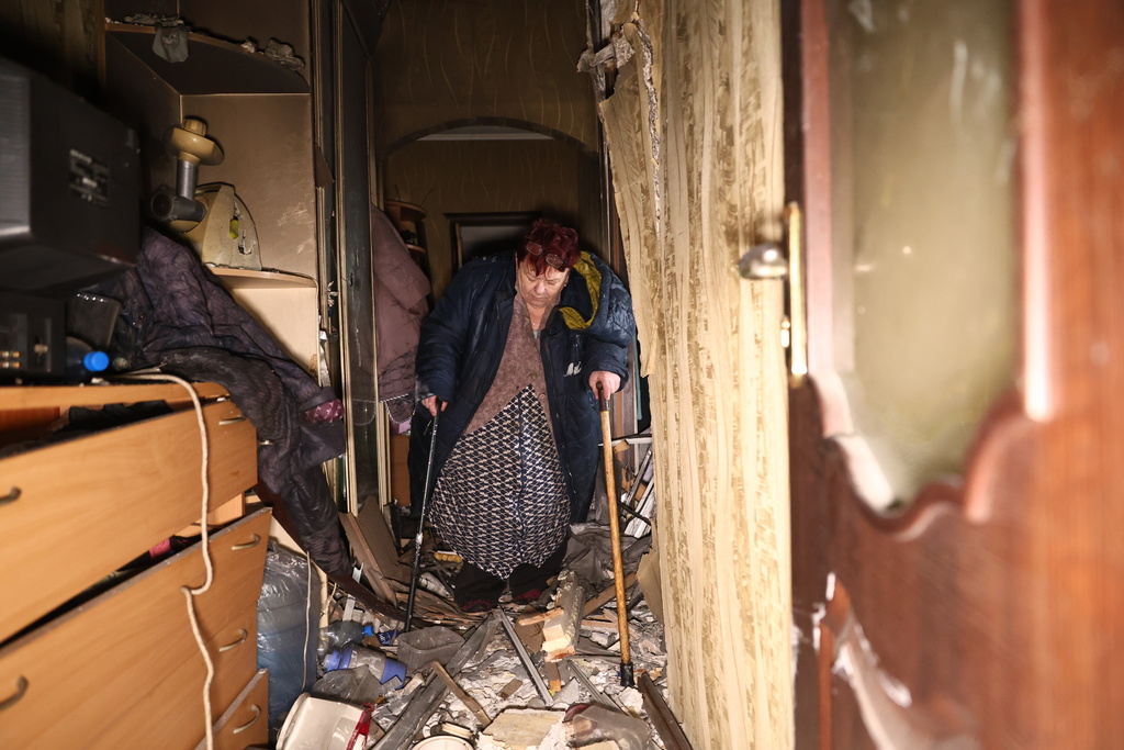 An elderly woman hobbles on crutches inside her damaged apartment after a Russian drone hit an apartment building in Zaporizhzhia, Ukraine, Thursday, Feb. 26, 2026. (AP Photo/Kateryna Klochko)