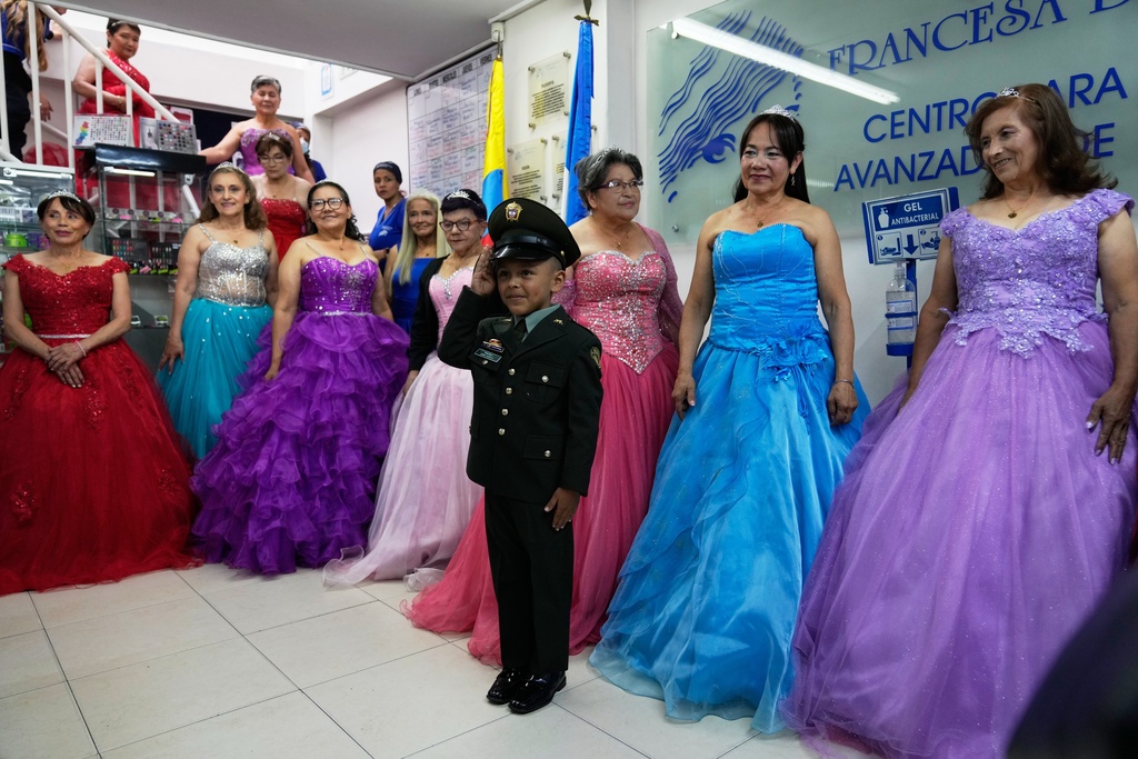 A boy escorts Rosalba Casas, right, and other women who never had a traditional 15th birthday party during a quinceanera celebration organized by the Suenos Hechos foundation in Bogota, Colombia, Friday, Oct. 24, 2025. (AP Photo/Fernando Vergara)