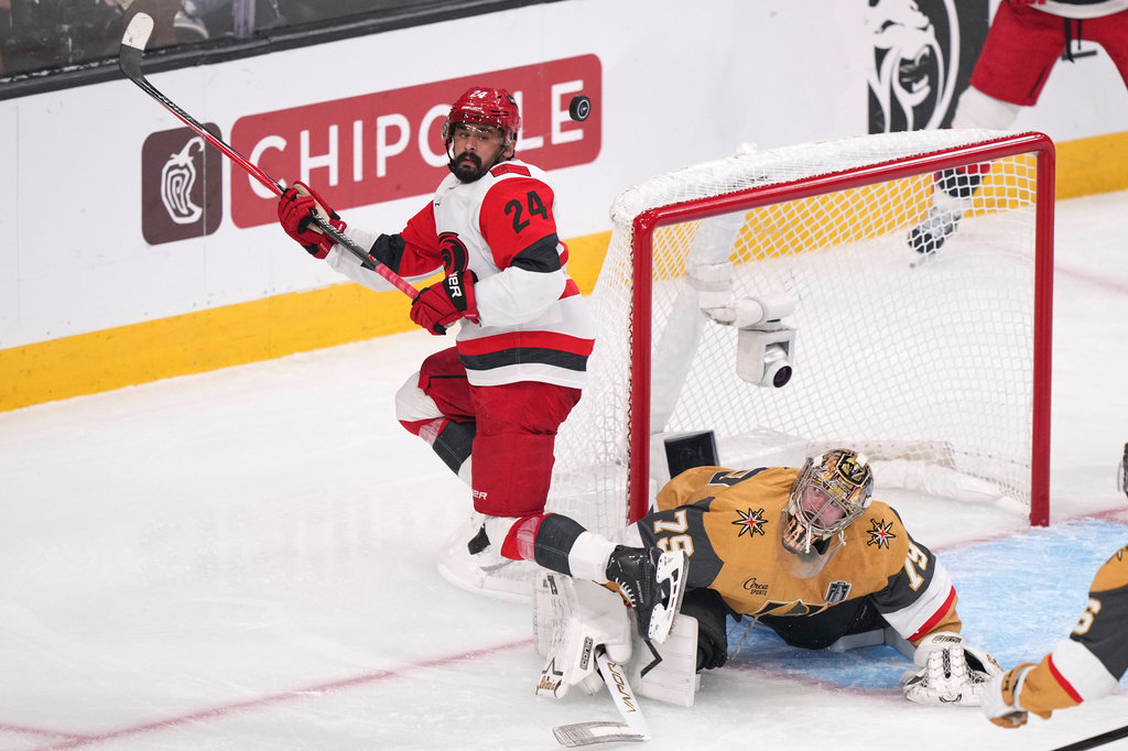 FILE - Carolina Hurricanes right wing Seth Jarvis, left, tries to know a the puck out of the air as Vegas Golden Knights goaltender Carter Hart defends during the third period in Game 4 of the NHL hockey Stanley Cup Final series June 9, 2026, in Las Vegas. (AP Photo/Candice Ward, File)