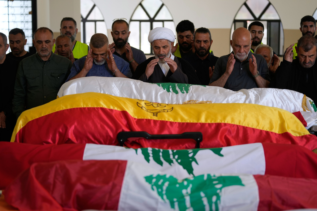 Mourners pray over the bodies of family members killed on Wednesday when their car was struck in an Israeli airstrike on a highway as they fled their village, during a funeral procession in the southern port city of Tyre, Lebanon, Friday, May 29, 2026. (AP Photo/Mohammed Zaatari)