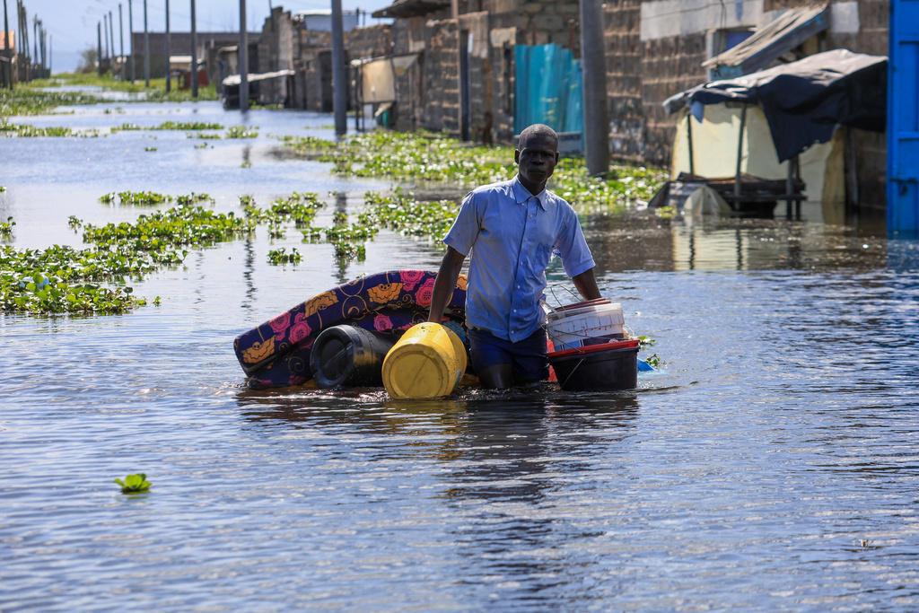 A man salvages his belongings after Lake Naivasha swelled and inundated homes, displacing hundreds in Kihoto Village, in Naivasha, Kenya's Rift Valley region, on Tuesday, Nov. 11, 2025. (AP Photo/Andrew Kasuku)
