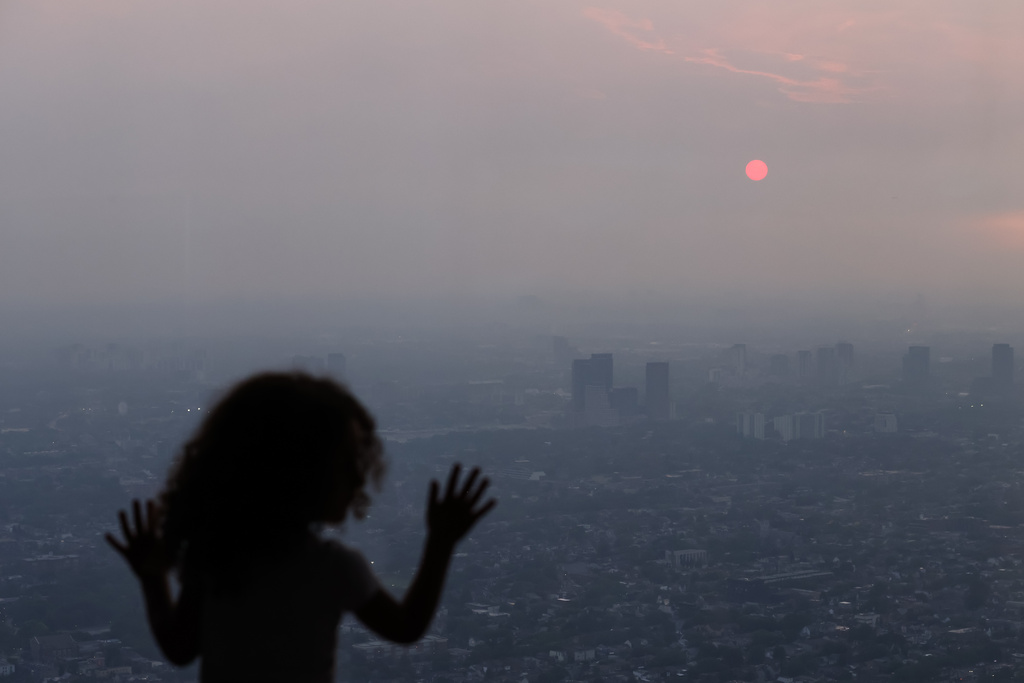 A child looks out from the observation deck of the CN Tower as smoke from wildfires in Northwestern Ontario blankets the city of Toronto, Thursday, July 16, 2026. (Cole Burston/The Canadian Press via AP)