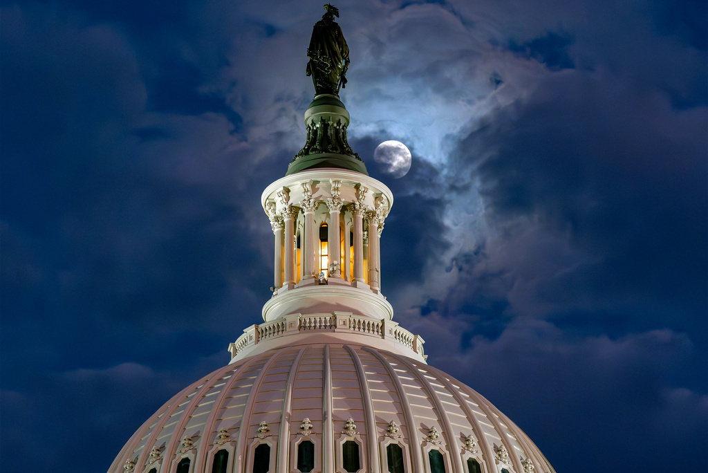 FILE - The moon emerges from the clouds over the U.S. Capitol dome in Washington, Dec. 2, 2025. (AP Photo/J. Scott Applewhite, File)