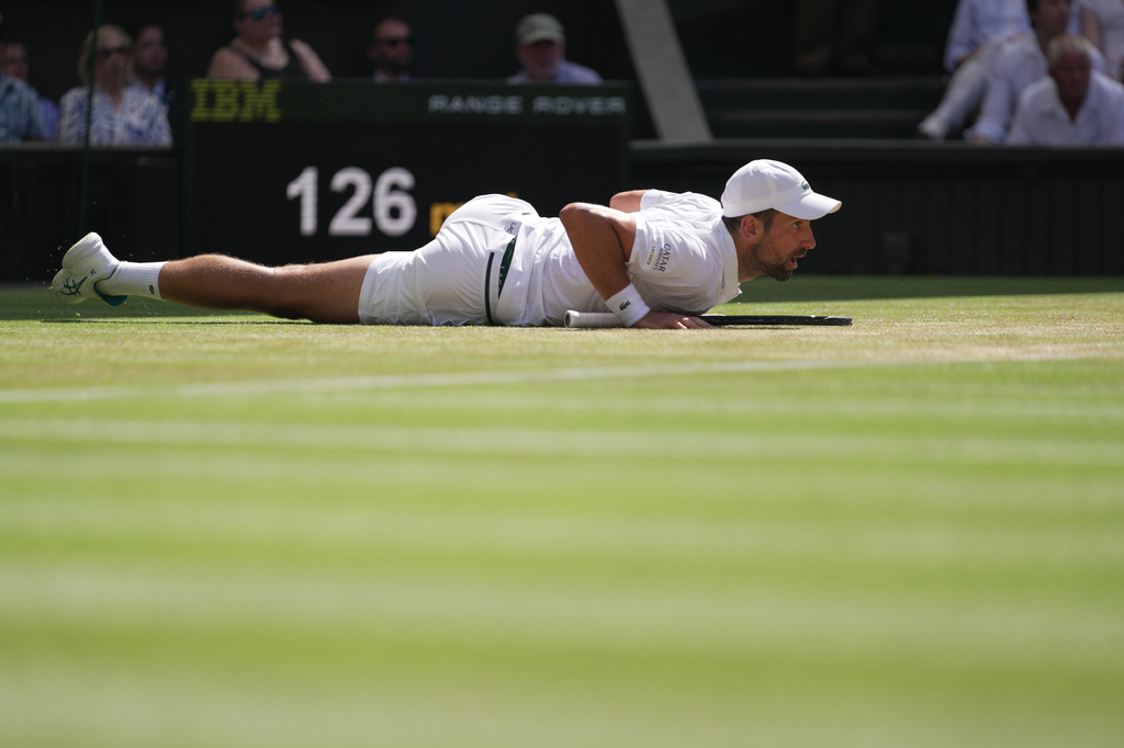 Novak Djokovic of Serbia falls over during a point against Roman Saffiullin of Russia in their fourth round men's singles match at the Wimbledon Tennis Championships in London, Sunday, July 5, 2026. (AP Photo/Brian Inganga)