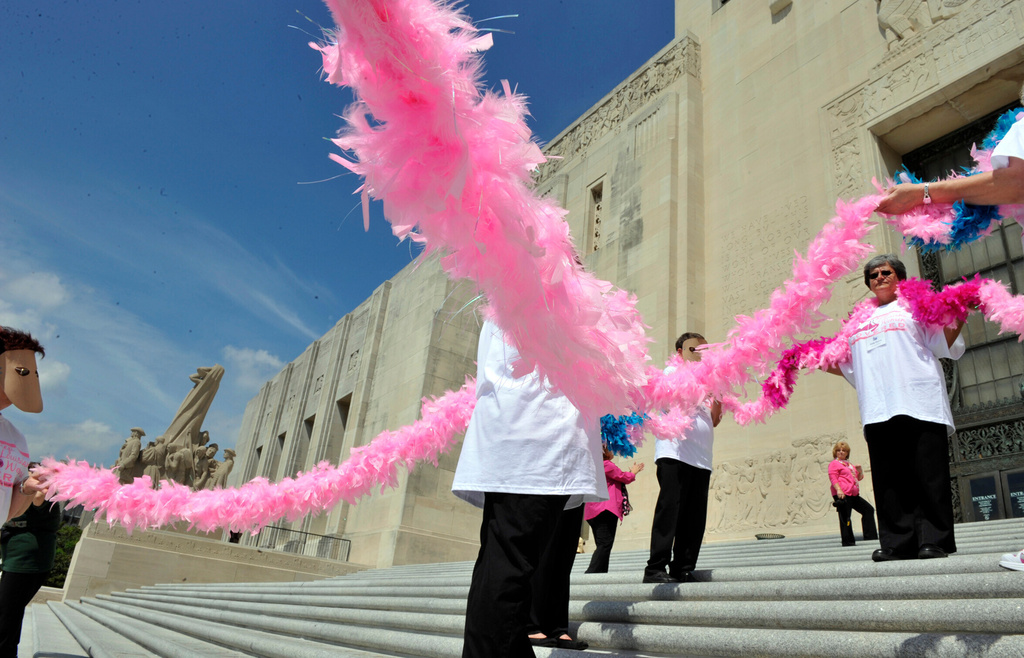 FILE - People hold a large pink feather ribbon for emphasis while gathering for a rally on the State Capitol Building steps to bring awareness to Breast and Cervical Cancer screening budget cuts Wednesday March 28, 2012, in Baton Rouge, La. ( Bill Feig/The Advocate via AP, File)