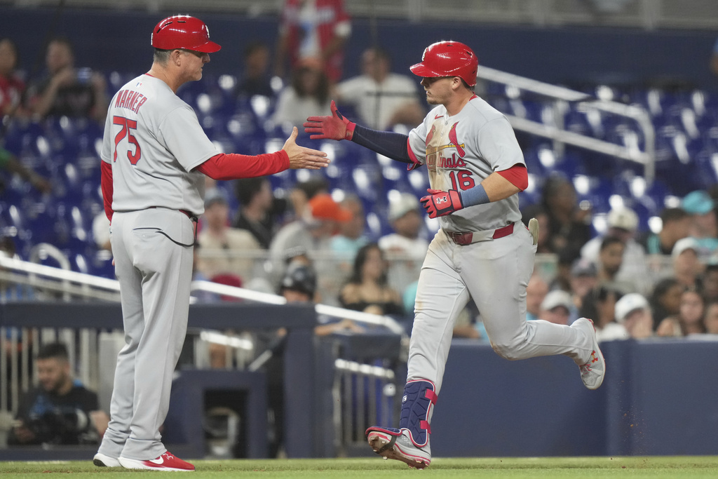 St. Louis Cardinals' Nolan Gorman (16) shakes hands with third base coach Ron Warner (73) after hitting a two run home run during the ninth inning of a baseball game against the Miami Marlins, Monday, Aug. 18, 2025, in Miami. (AP Photo/Lynne Sladky)