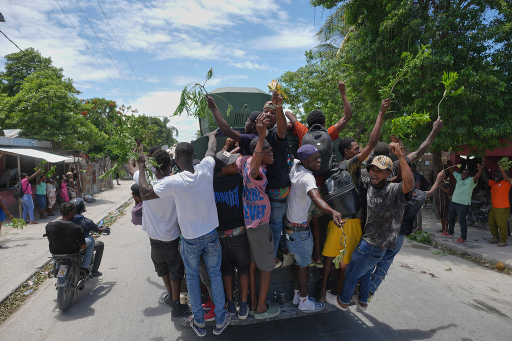 Residents of Cité Soleil celebrate the arrival of armored police vehicles during a protest to demand that police officers go and fight the gangs that control their neighborhood, in Port-au-Prince, Haiti, Tuesday, May 12, 2026. (AP Photo/Odelyn Joseph)