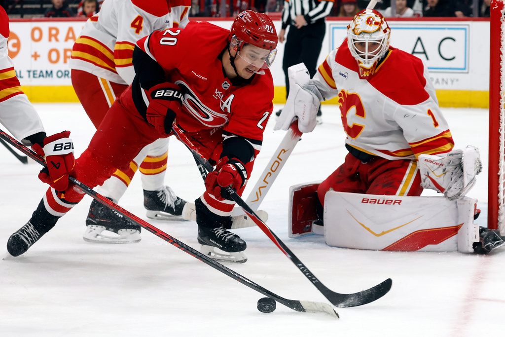 Carolina Hurricanes' Sebastian Aho (20) looses control of the puck near Calgary Flames goaltender Devin Cooley (1) during the second period of an NHL hockey game in Raleigh, N.C., Sunday, Nov. 30, 2025. (AP Photo/Karl DeBlaker)
