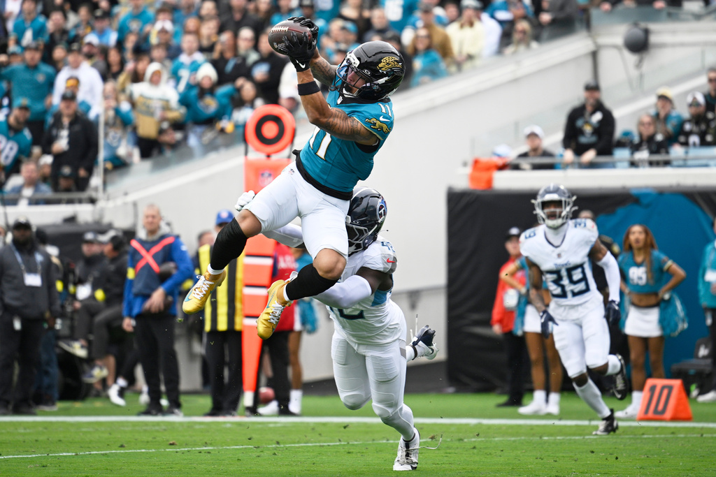 Jacksonville Jaguars wide receiver Parker Washington (11) makes a catch for a touchdown over Tennessee Titans safety Sanoussi Kane, below, during the first half of an NFL football game Sunday, Jan. 4, 2026, in Jacksonville, Fla. (AP Photo/Phelan M. Ebenhack)