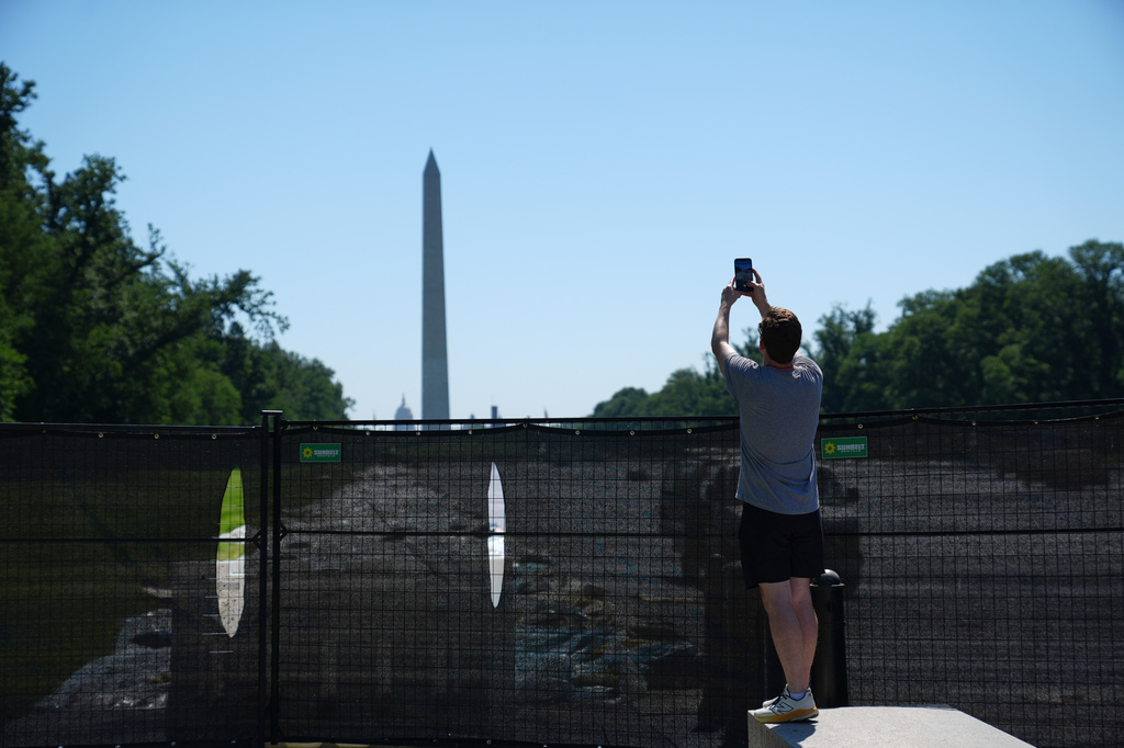 The Washington Monument is seen as an unidentified man takes a picture of work being done at the Lincoln Memorial Reflecting Pool, Thursday, June 4, 2026 in Washington. (AP Photo/Stephanie Scarbrough)