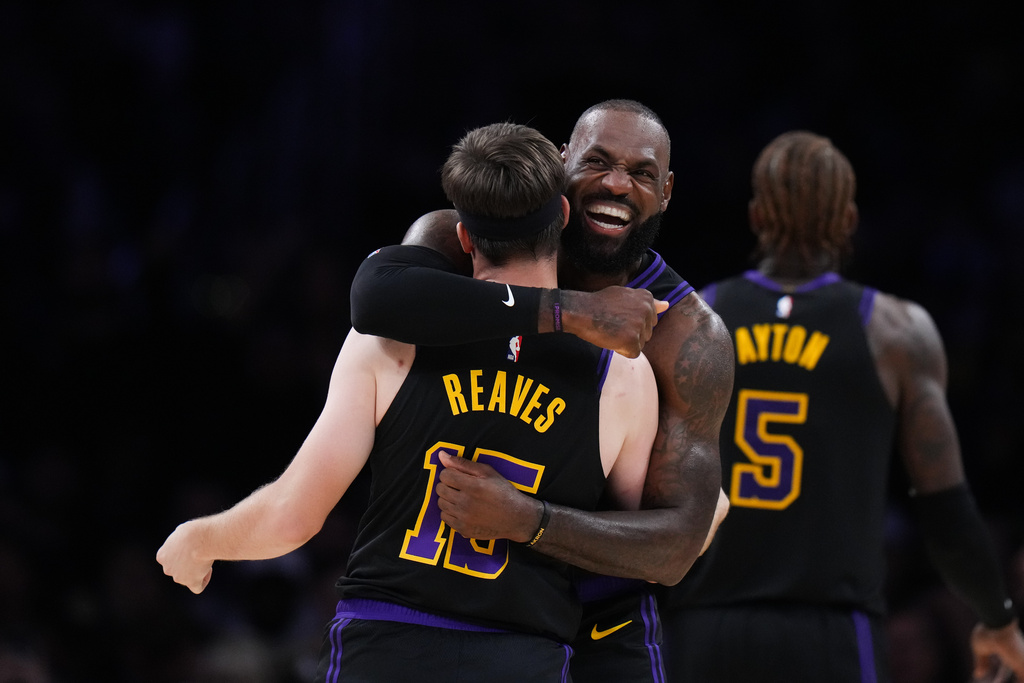Los Angeles Lakers guard Austin Reaves (15) is embraced by forward LeBron James after Reaves made a three-point basket during the first half of an NBA basketball game against the Utah Jazz Tuesday, Nov. 18, 2025, in Los Angeles. (AP Photo/Jae C. Hong)