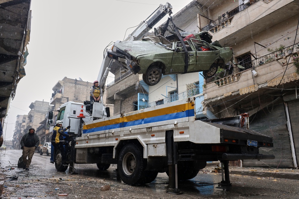 Civil Defense remove a damaged car in the predominantly Kurdish Sheikh Maqsoud neighborhood where clashes broke out Tuesday Jan. 6 between government forces and the Kurdish-led Syrian Democratic Forces in the northern city of Aleppo, Syria, Monday, Jan. 12, 2026. (AP Photo/Omar Albam)