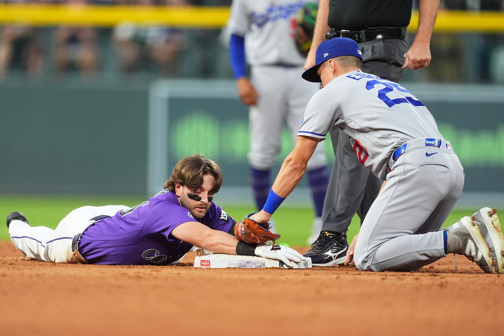 Colorado Rockies' Connor Norby, left, slides safely into second base with an RBI double as Los Angeles Dodgers second baseman Tommy Edman applies a late tag in the third inning of a baseball game Tuesday, Aug. 18, 2026, in Denver. (AP Photo/David Zalubowski)
