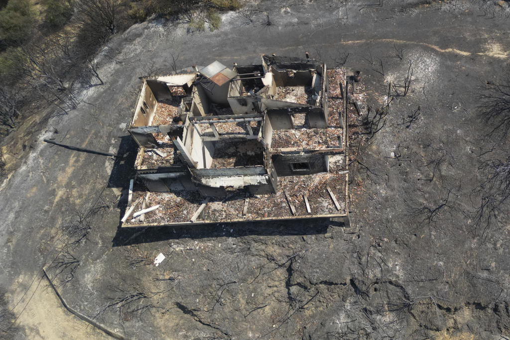 A burned house on a hill is seen from above in Kaminia seaside village, during a wildfire near Patras city, western Greece, Wednesday, Aug. 13, 2025. (AP Photo/Thanassis Stavrakis)