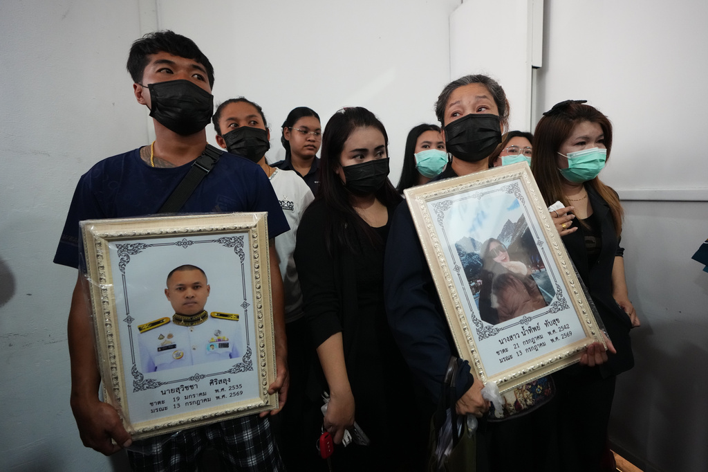 Relatives of a victim in a music bar fire hold portraits of husband Suvitcha Sirisalung and wife Namthip Tubsuk while receiving the victims' bodies at a police hospital in Bangkok, Thailand, Tuesday, July 14, 2026. (AP Photo/Sakchai Lalit)