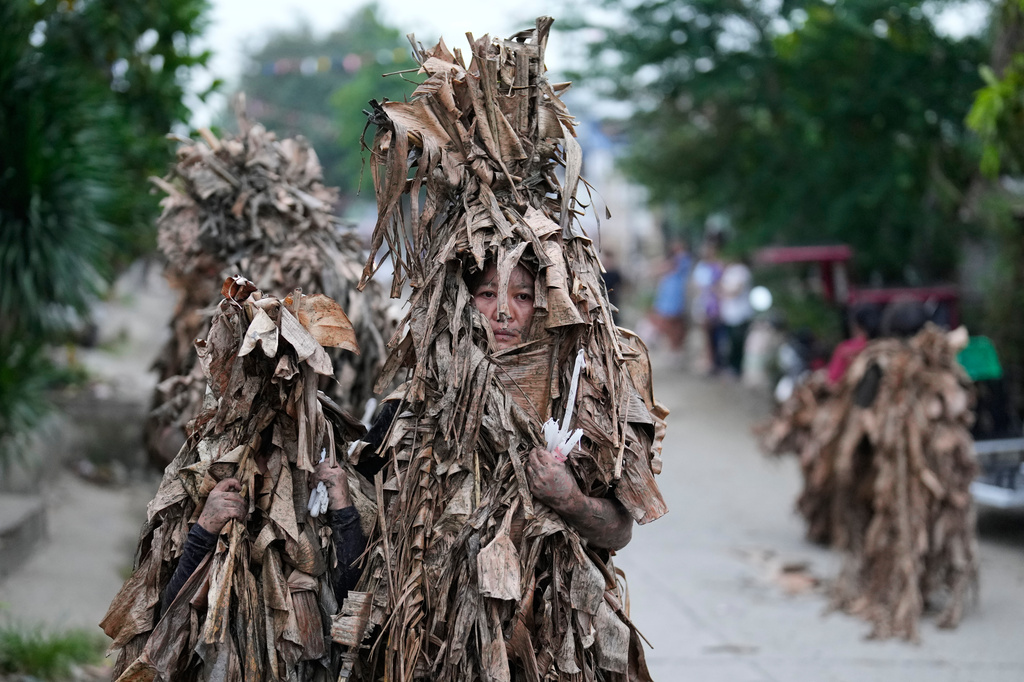 Catholic devotees covered in mud and dried banana leaves join the mud people festival on the feast day of Saint John the Baptist at Bibiclat, Nueva Ecija province, northern Philippines on Wednesday, June 24, 2026. (AP Photo/Aaron Favila)