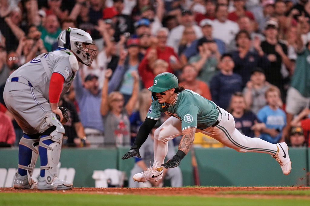 Boston Red Sox's Jarren Duran, right, beats the throw to Toronto Blue Jays' Alejandro Kirk, left, while scoring on a double by Anthony Seigler during the eighth inning of a baseball game, Friday, July 24, 2026, in Boston. (AP Photo/Charles Krupa)