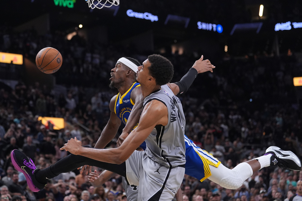 Golden State Warriors forward Jimmy Butler III, left, is blocked by San Antonio Spurs forward Victor Wembanyama (1) as he drives to the basket during the second half of an NBA Cup basketball game in San Antonio, Friday, Nov. 14, 2025. (AP Photo/Eric Gay)