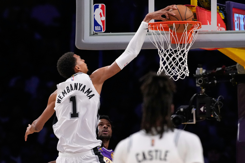 San Antonio Spurs forward Victor Wembanyama, left, goes up fora dunk as Los Angeles Lakers guard Bronny James defends during the first half of an NBA basketball game Wednesday, Nov. 5, 2025, in Los Angeles. (AP Photo/Mark J. Terrill)