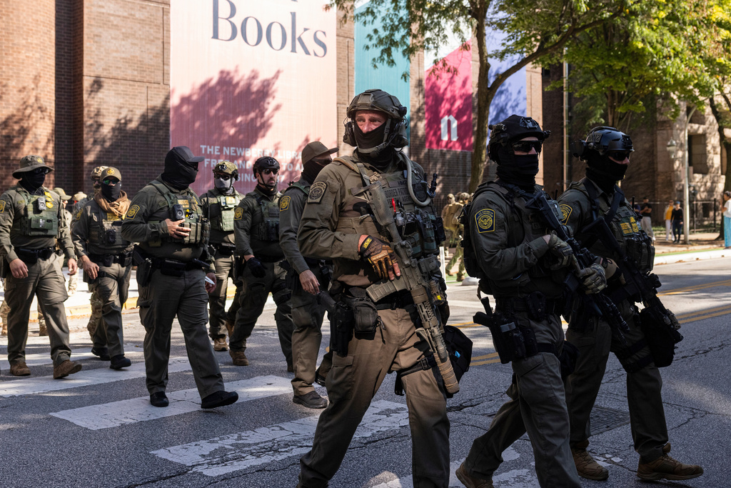 Federal agents from U.S. Immigration and Customs Enforcement and U.S. Customs and Border Protection cross North Clark Street at West Oak Street in River North, Sunday, Sept. 28, 2025, in Chicago. (Ashlee Rezin/Chicago Sun-Times via AP)