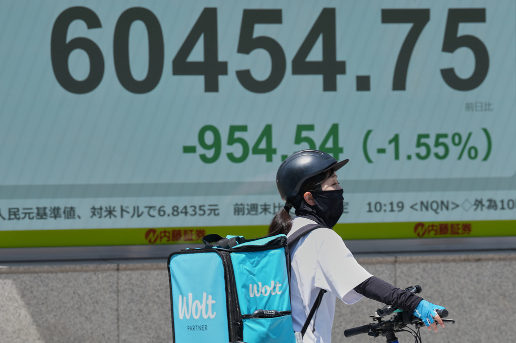 A delivery person on a bicycle waits for a traffic light near an electronic stock board showing Japan's Nikkei index at a securities firm Monday, May 18, 2026, in Tokyo. (AP Photo/Eugene Hoshiko)