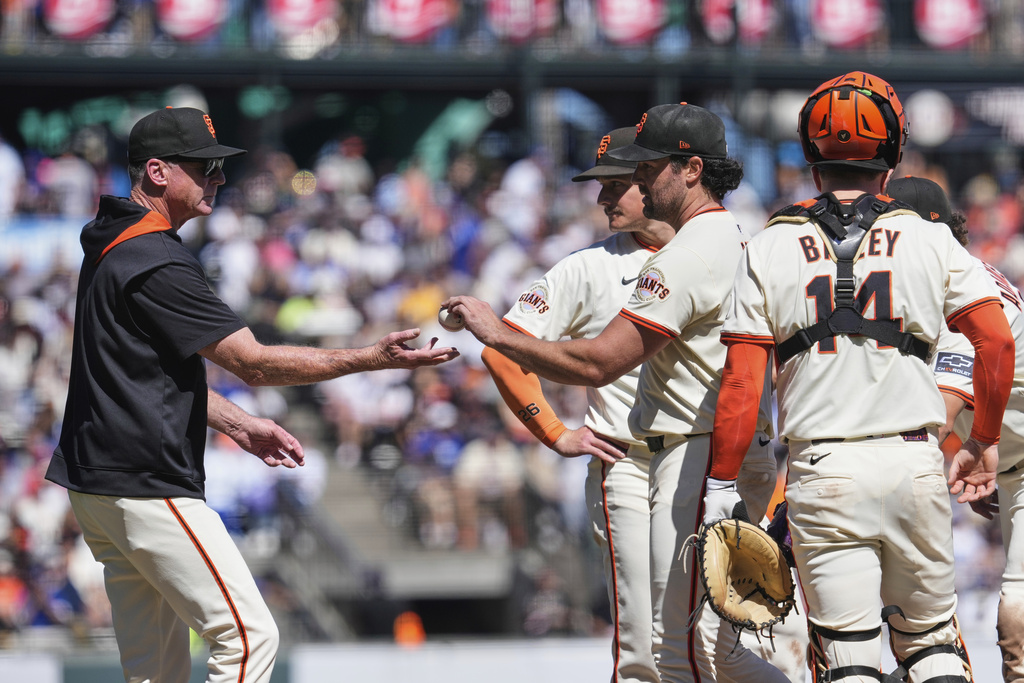 San Francisco Giants pitcher Robbie Ray, third from right, hands the ball over to manager Bob Melvin, left, as he exits during the fifth inning of a baseball game against the Los Angeles Dodgers, Sunday, Sept. 14, 2025, in San Francisco. (AP Photo/Godofredo A. Vásquez)
