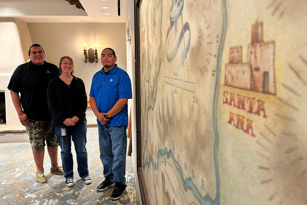 Santa Ana Pueblo Tribal Historic Preservation Department staff members, from left to right, technician Thomas Armijo, director Monica Murrell and coordinator Jarrett Lujan pose for a photograph in front a map in Santa Ana Pueblo, N.M., on Monday, June 30, 2025. (AP Photo/Susan Montoya Bryan)