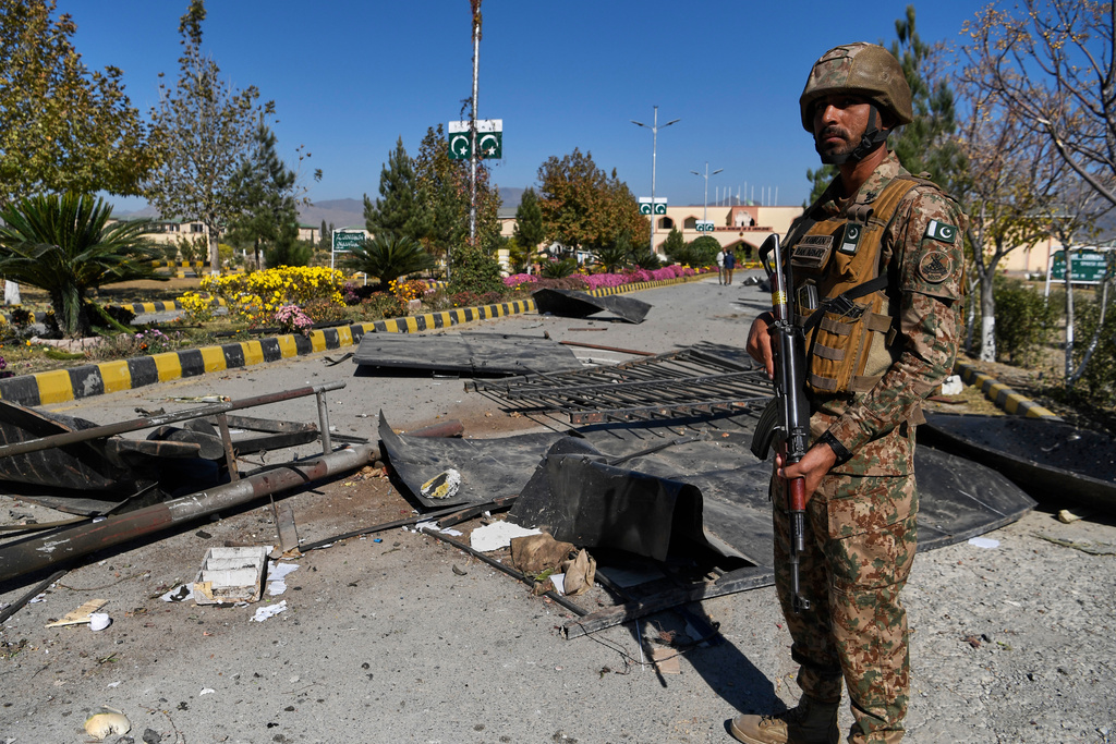 An Army soldier stands guard next to damages at the main gate of an army-run cadet college that was assaulted by militants on Monday, in Wana, a city in the northwestern Pakistani district South Waziristan bordering with Afghanistan, Thursday, Nov. 13, 2025. (AP Photo/Ahsan Shahzad)