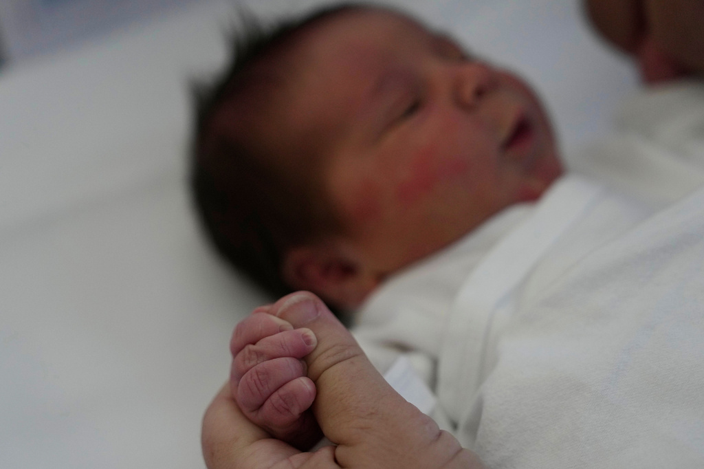 Cristina Rapti-Tzelepi, 54, holds the hand of her three-day-old daughter, Georgia, at a private maternity clinic in Athens, Greece, Friday, Sept. 11, 2026. (AP Photo/Thanassis Stavrakis)