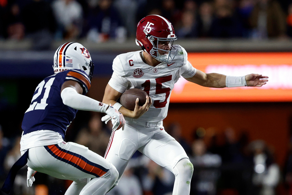 Alabama quarterback Ty Simpson (15) carries the ball for a first down as Auburn safety Anquon Fegans (21) defends during the second half of an NCAA college football game, Saturday, Nov. 29, 2025, in Auburn, Ala. (AP Photo/Butch Dill)