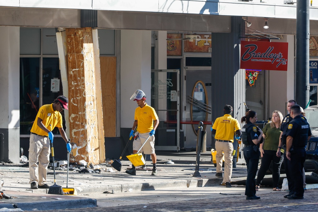 People clean up the damage from a car that crashed into a local business, while law enforcement investigate the scene on Saturday, Nov. 8, 2025, in Tampa, Fla. (Jefferee Woo/Tampa Bay Times via AP)