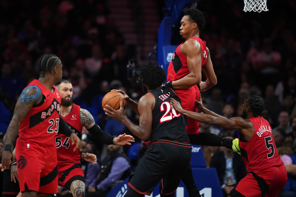 Philadelphia 76ers' Joel Embiid (21) tries to get a shot past Toronto Raptors' Scottie Barnes (4), and Immanuel Quickley (5) during the second half of an NBA basketball game Saturday, Nov. 8, 2025, in Philadelphia. (AP Photo/Matt Slocum)