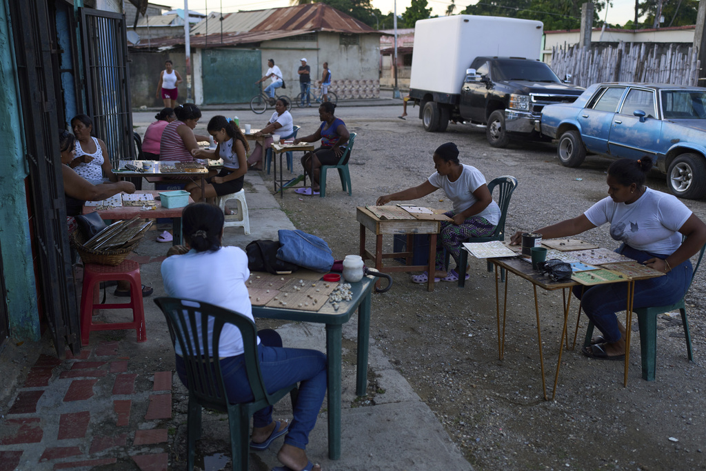 Women play bingo on a street in Güiria, on Venezuela's Paria Peninsula, Saturday, Sept. 13, 2025. (AP Photo/Ariana Cubillos)