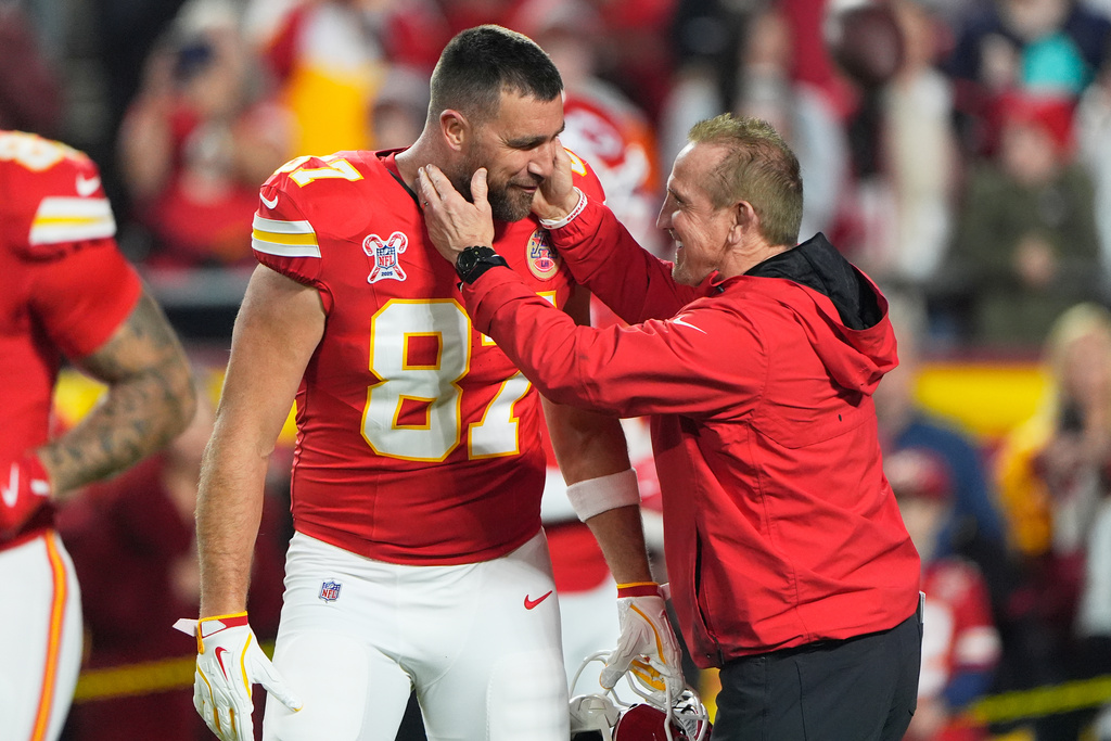 Kansas City Chiefs tight end Travis Kelce, left, talks with defensive coordinator Steve Spagnuolo prior to an NFL football game against the Denver Broncos Thursday, Dec. 25, 2025, in Kansas City, Mo. (AP Photo/Charlie Riedel)