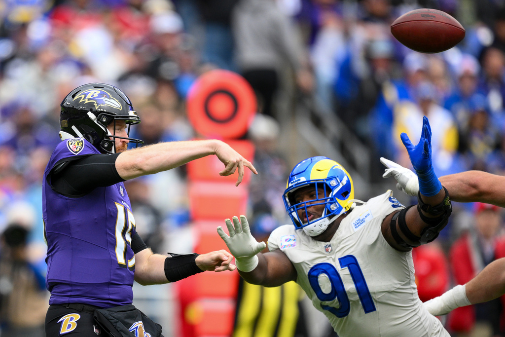 Baltimore Ravens quarterback Cooper Rush, left, attempts a pass as Los Angeles Rams defensive end Kobie Turner (91) applies pressure during the first half of an NFL football game Sunday, Oct. 12, 2025, in Baltimore. (AP Photo/Nick Wass)