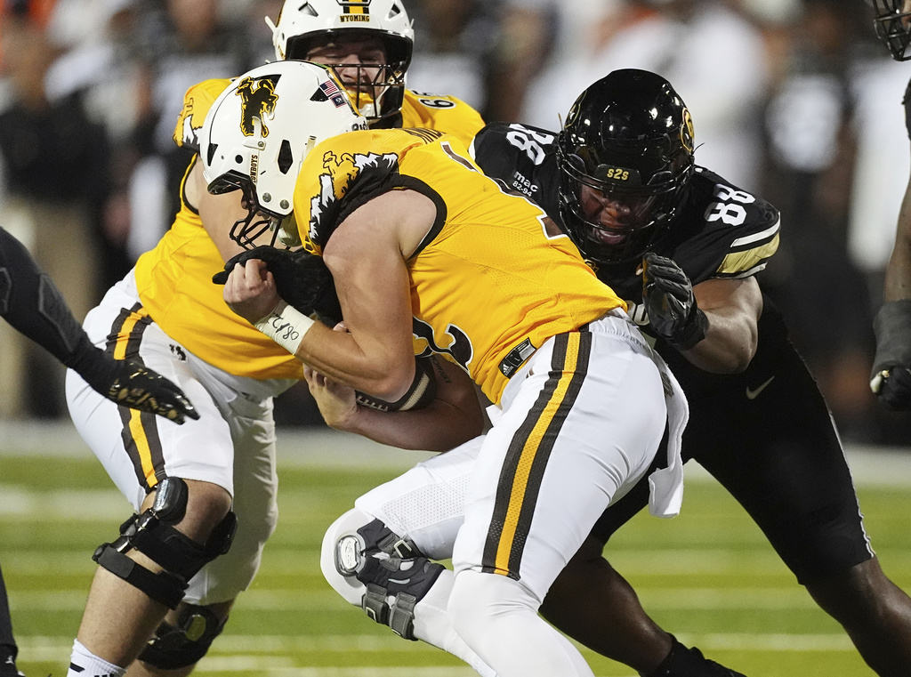 Wyoming quarterback Kaden Anderson, front, is stopped after a short gain by Colorado defensive tackle Amari McNeill (88) in the first half of an NCAA college football game Saturday, Sept. 20, 2025, in Boulder, Colo. (AP Photo/David Zalubowski)