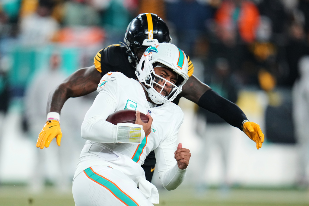 Miami Dolphins quarterback Tua Tagovailoa (1) carries the ball as Pittsburgh Steelers linebacker Patrick Queen, rear, moves in to make the stop in the first half of an NFL football game in Pittsburgh, Monday, Dec. 15, 2025. (AP Photo/Gene J. Puskar)