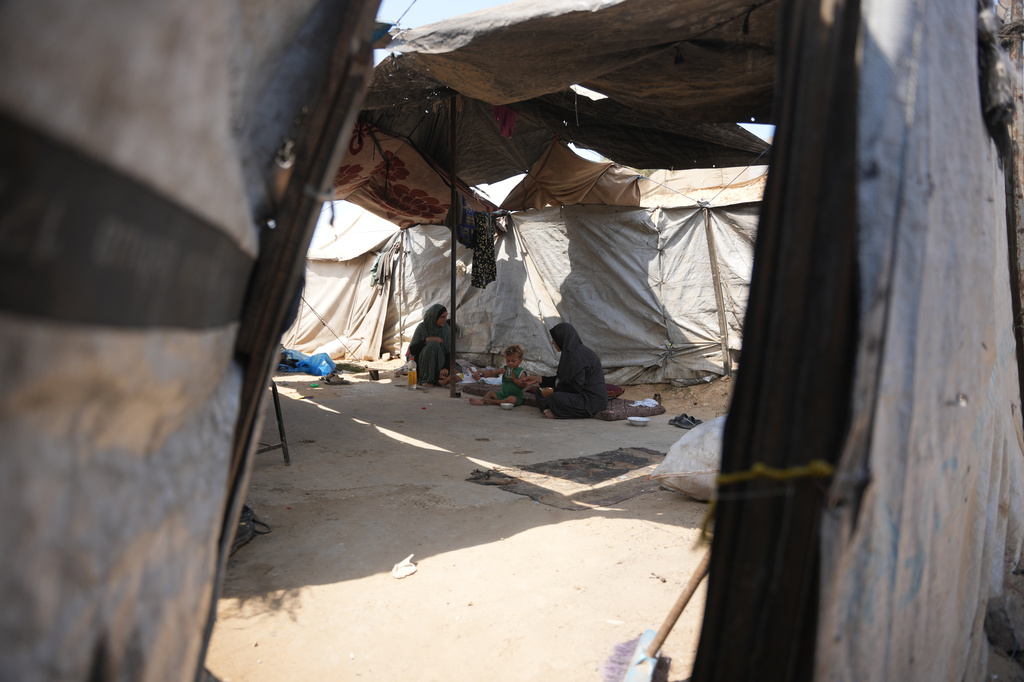 A Palestinian woman feeds a child a meal cooked using combustible materials collected from a garbage dump amid a shortage of cooking gas at a tent in Deir al-Balah, central Gaza Strip, Saturday, Aug. 22, 2026. (AP Photo/Abdel Kareem Hana)