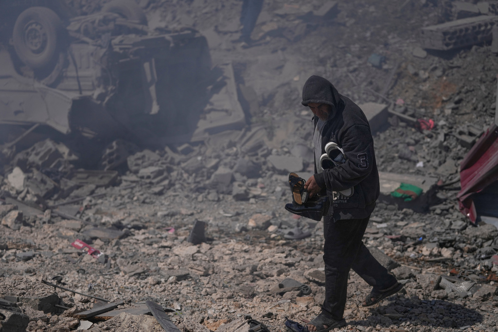 A man carries shoes from his destroyed house that was hit by Israeli airstrikes hit several houses in Sir al-Gharbiyeh village south Lebanon, Sunday, March, 8, 2026. (AP Photo/Mohammed Zaatari)
