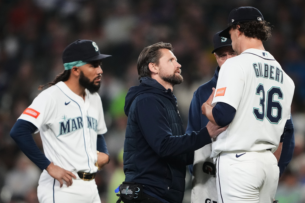 Seattle Mariners head athletic trainer Kyle Torgerson checks on starting pitcher Logan Gilbert after Athletics' Carlos Cortes hit a line drive into his jersey during the first inning of a baseball game, Wednesday, April 22, 2026, in Seattle. (AP Photo/Lindsey Wasson)