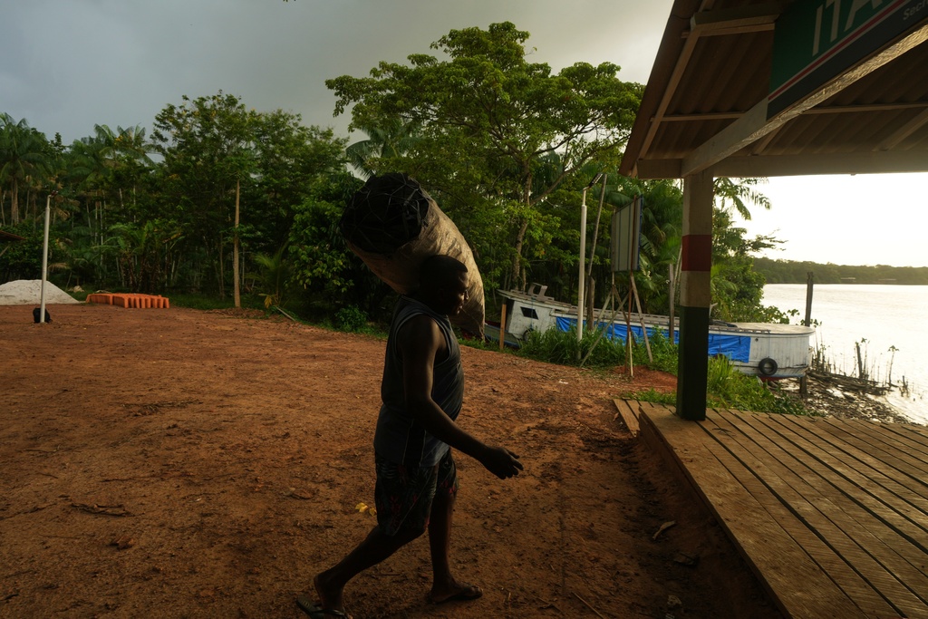 A man carries a charcoal sack to the harbor in Itacoa Miri, Brazil, Tuesday, Nov. 18, 2025, to be shipped for sale in Belem. (AP Photo/Fernando Llano)