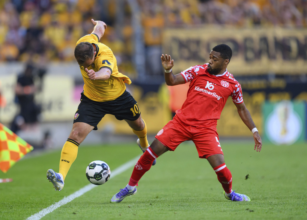 Dresden's Jakob Lemmer, left, and Mainz' Arnaud Nordin, right, challenge for the ball during the German soccer cup first round match between Dynamo Dresden and FSV Mainz 05 in Dresden, Germany, Monday, Aug. 18, 2025. (Robert Michael/dpa via AP)