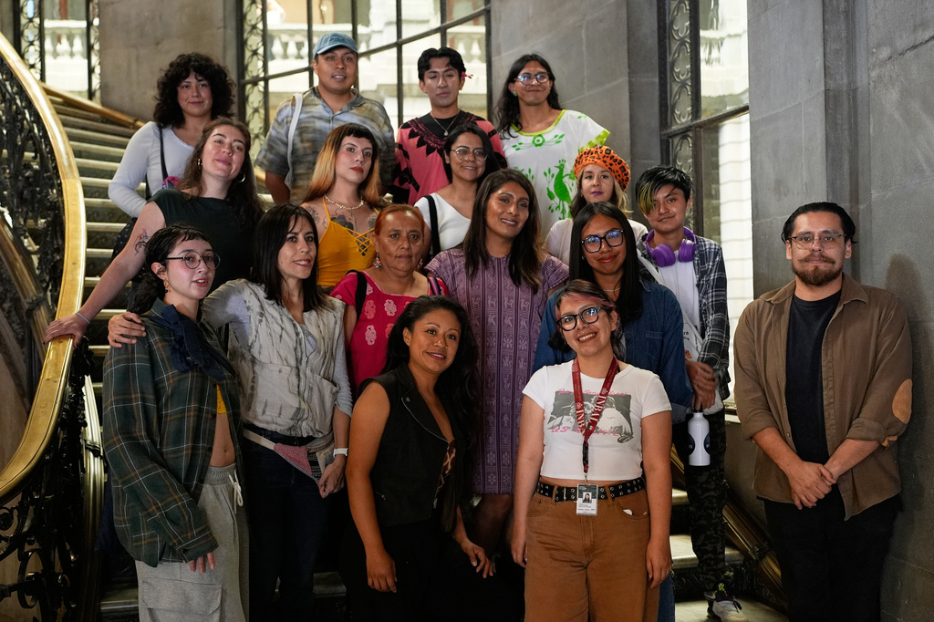 People pose for a photo after a backstrap loom workshop for LGBTQ+ people by Muxe artist Xaneri Merino, in purple, in Mexico City, Tuesday, April 14, 2026. (AP Photo/Marco Ugarte)